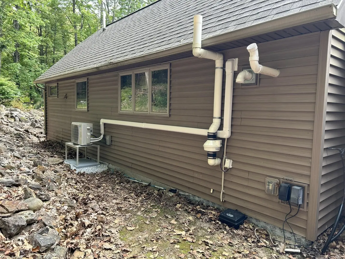 Heat-pump condenser installed beside a brown home
