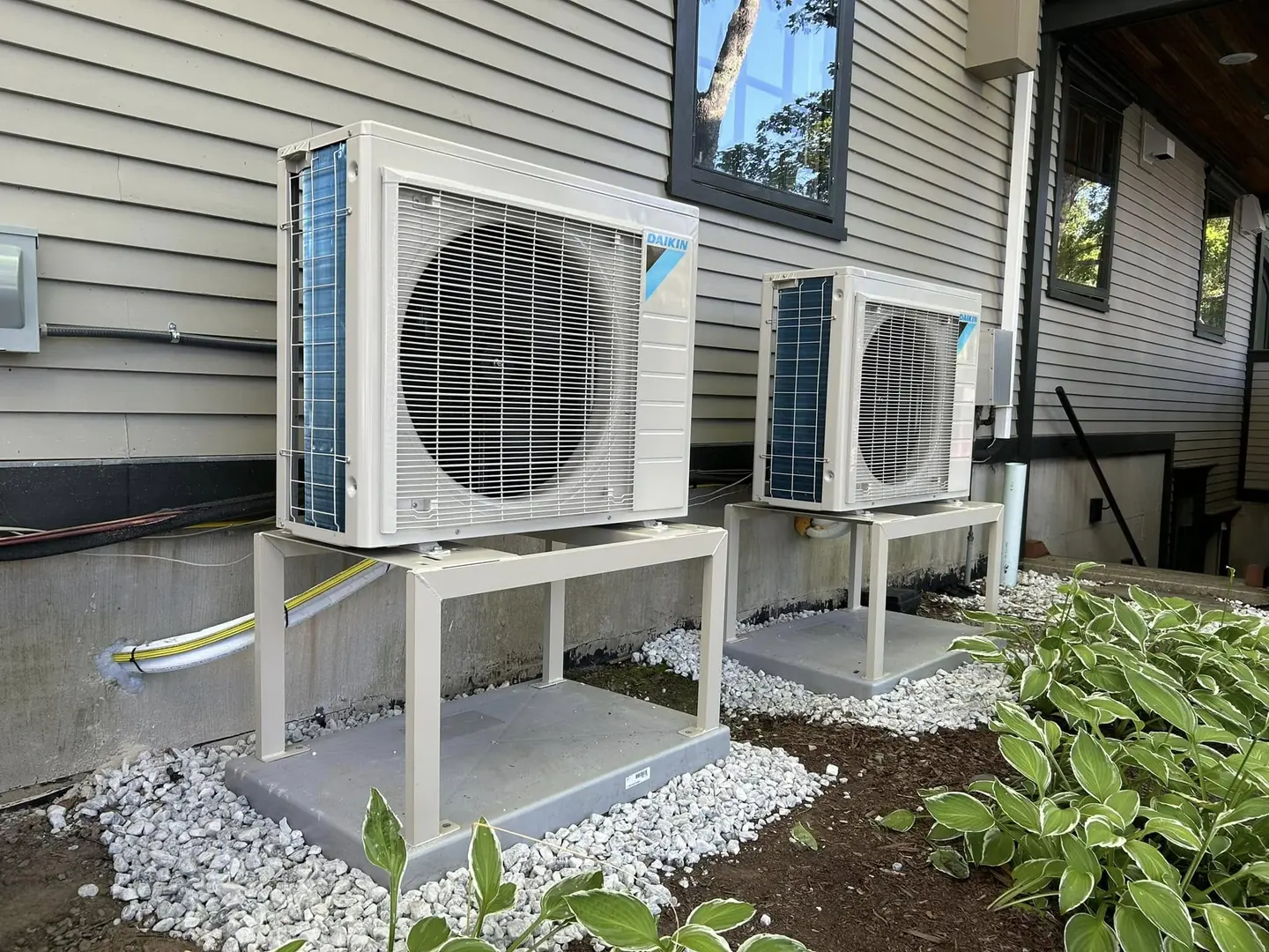 Two outdoor heat-pump units along a home